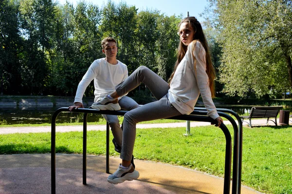 Uma jovem e um jovem com as mesmas roupas no parque infantil . — Fotografia de Stock