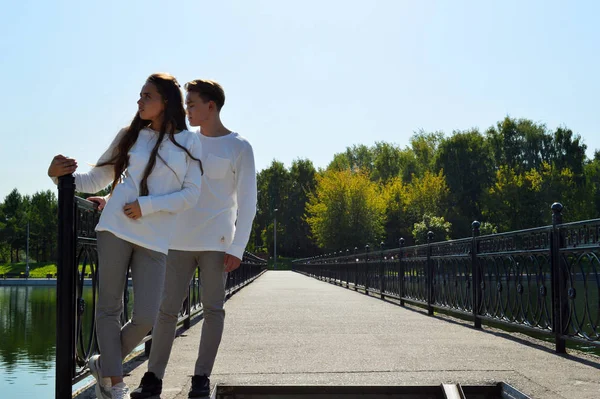 一个年轻的女孩和一个穿着同一件衣服的年轻人在水边的一座桥上 — 图库照片
