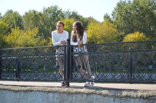 一个年轻的女孩和一个穿着同一件衣服的年轻人在水边的一座桥上 — 图库照片