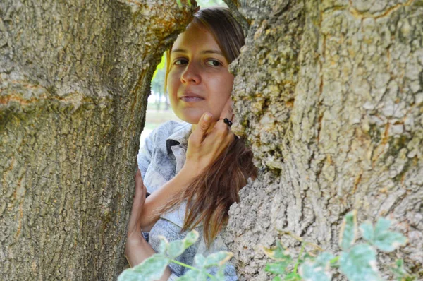 Siyah Saçlı Sarı Tişörtlü Bir Kadın Ağaçtan Bakıyor — Stok fotoğraf