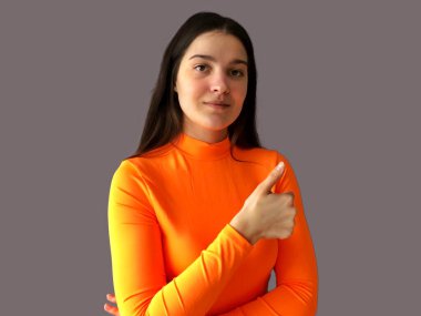 Koyu renk saçlı, parlak turuncu kazaklı, gri arka planda güzel bir kız.