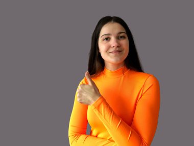 Koyu renk saçlı, parlak turuncu kazaklı, gri arka planda güzel bir kız.