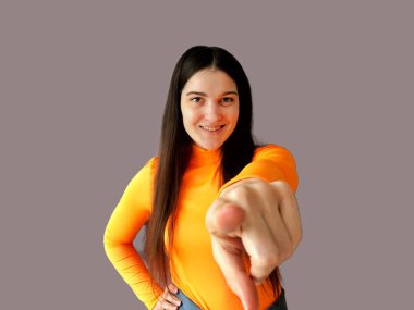 Koyu renk saçlı, parlak turuncu kazaklı, gri arka planda güzel bir kız.