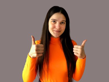 Gri arka planda parlak turuncu süveter giyen koyu renk saçlı güzel bir kız. Sınıfı gösterir