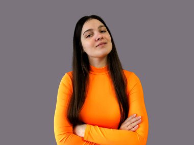 Koyu renk saçlı, parlak turuncu kazaklı, gri arka planda güzel bir kız.