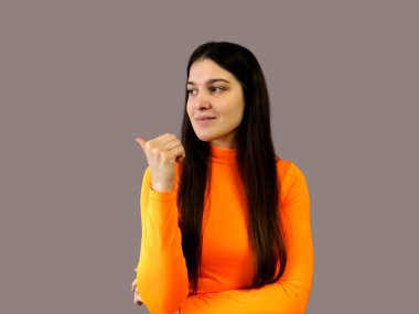 Koyu renk saçlı, parlak turuncu kazaklı, gri arka planda güzel bir kız.