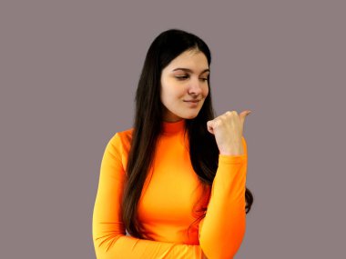 Koyu renk saçlı, parlak turuncu kazaklı, gri arka planda güzel bir kız.