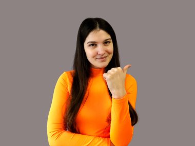 Koyu renk saçlı, parlak turuncu kazaklı, gri arka planda güzel bir kız.