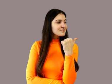 Koyu renk saçlı, parlak turuncu kazaklı, gri arka planda güzel bir kız.