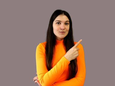 Koyu renk saçlı, parlak turuncu kazaklı, gri arka planda güzel bir kız.