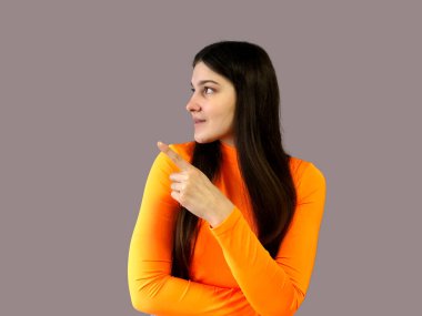 Koyu renk saçlı, parlak turuncu kazaklı, gri arka planda güzel bir kız.