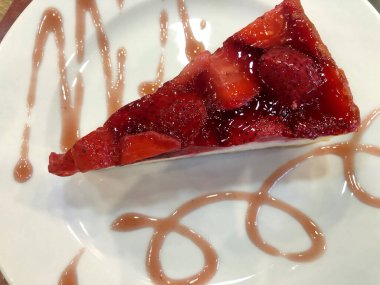 Tabağında çilek olan lezzetli bir peynirli kek.