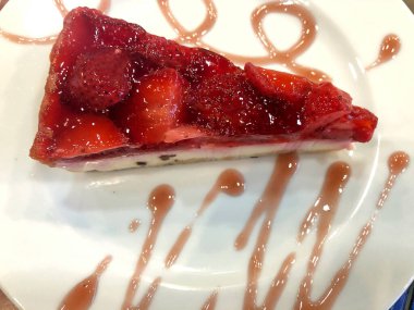 Tabağında çilek olan lezzetli bir peynirli kek.