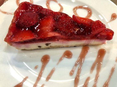 Tabağında çilek olan lezzetli bir peynirli kek.