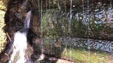 Yıpranmış ahşap bir kanal kilidinin yarığından akan suyun yakın çekimi. Güçlü yüksek basınçlı su sıçrıyor ve beyaz kabarcıklar oluşturuyor.