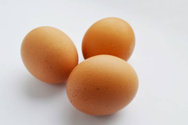 Yakından bakıldığında, beyaz üzerine izole edilmiş üç kahverengi yumurta görünüyor.