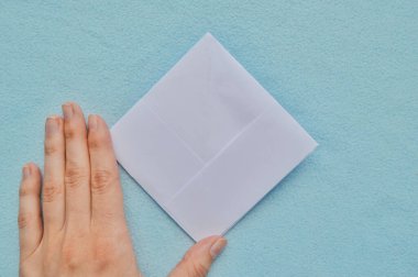 Kağıt tekne adım adım. Mavi arka planda beyaz kağıt. Beşinci adım.