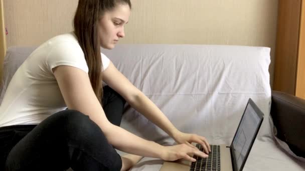 一个黑头发的年轻漂亮的女孩正坐在笔记本电脑旁 在家工作 远程工作 远程学习 — 图库视频影像