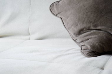 Aydınlık bir kanepede gri bir yastık. Uluslararası Kayıp Çocuklar Günü