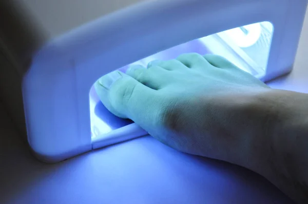 Pedicure foot and nails treatment with UV lamp. Spa at home