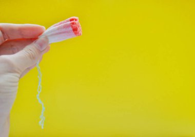 Kadın eli sarı arka planda kullanılmış bir jigolojik tampon tutuyor.