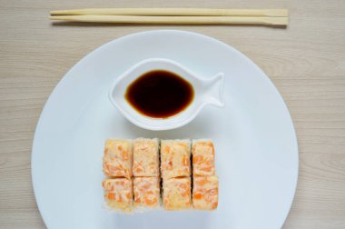 Suşi beyaz bir tabakta. Beyaz tabakta somonlu rulo.