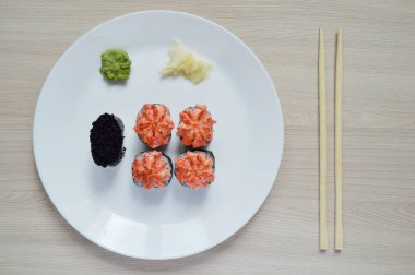 Suşi beyaz bir tabakta. Beyaz tabakta siyah havyarlı fırında ekmek ve suşi.