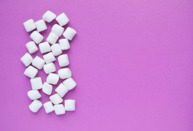 Marshmallow ile boşaltmak pembe arka plan üzerinde. Düz yatıyordu veya en iyi görünümü. Arka plan veya doku renkli mini lokum gibiydi. Kış yiyecek arka plan kavramı.