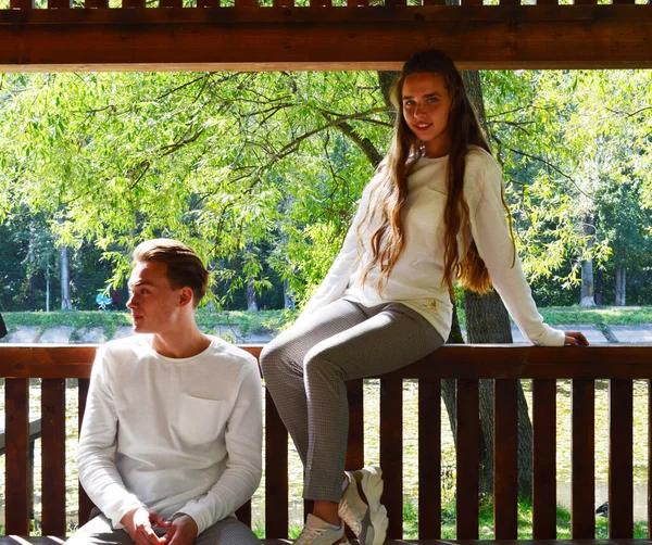 Une Jeune Fille Et Un Jeune Homme Dans Les Memes Vetements Assis Sur Un Banc En Bois Modele Tshirt Stock Photo 345212124
