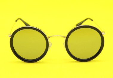 Modern güneş gözlüğü. Yuvarlak lensler. Sarı arka planda şık gözlükler..