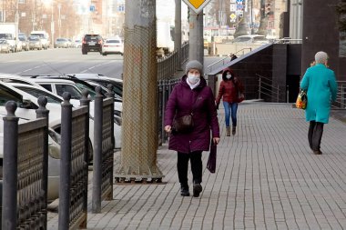 MOSCOW, Rusya - Nisan, 2020. COVID-19 virüsü yüzünden yüzünde solunum cihazı olan yetişkin bir kadın gün içinde caddede yürüyor. Giyim kuşam, bahar. Karantinaya alın. Halka açık yerlerde insanların hareketlerine kısıtlama