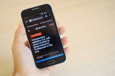 Los Angeles, ABD - 8 Nisan 2020. Elinde akıllı telefon, ekranda yeni haberler olan web sitesi - Görüntü