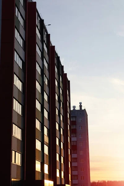 Tall multi-storey residential building on a sunset background. Buying and selling real estate