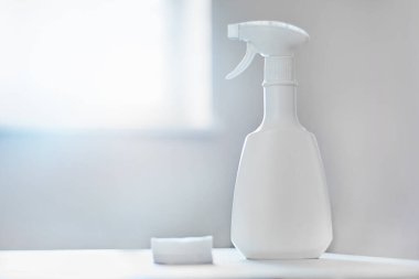 Deterjan ve dezenfektanlar için beyaz sprey. Parlak bir odadaki beyaz bir masanın üzerinde pamuk pedlerle. Arka planda bulanık bir pencere. Önleme ve sağlık güvenliği