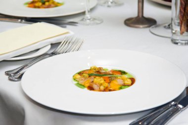 Hazır bir et, mısır ve sosun yakın plan çekimi. Bir restorandaki beyaz bir masada yuvarlak bir tabakta. Tatildeki bir ziyafetten önce.