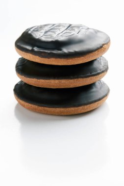 Çikolatayla kaplı yuvarlak bisküviler altta fotokopi alanı olan beyaz dikey arka planda üst üste yatıyorlar. Ev yapımı pasta ve tatlı yapma kavramı.