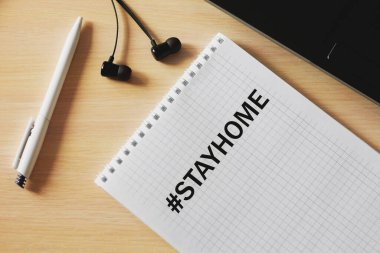 Notepad, kalem ve kulaklığın üst görüntüsü karantina sırasında evde kalır. Çalışma ve karantina süresince iş planlama ve eğitim kavramı