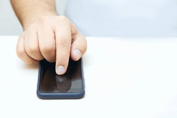 A person is holding a phone and tapping the screen on a white background with copy space. Concept of lifestyle business and mobile Internet technologies in the office