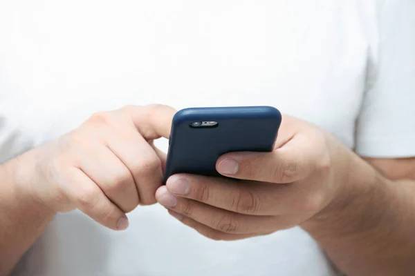 A person is holding a phone and tapping the screen on a white background with copy space. Concept of lifestyle business and mobile Internet technologies in the office