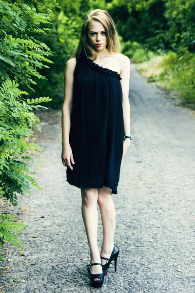 Vacker ung flicka poserar i svart klänning — Stockfoto