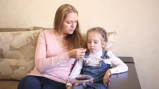 Mutter und Tochter essen Schokolade und schauen fern — Stockvideo