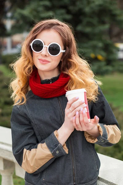Счастливая молодая женщина в солнечных очках, пьет кофе на открытом воздухе — стоковое фото