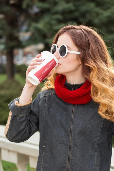 Glad ung kvinna i solglasögon, dricka kaffe utomhus — Stockfoto