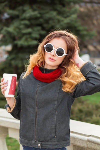 Lykkelig ung kvinde i solbriller, drikker kaffe udendørs - Stock-foto