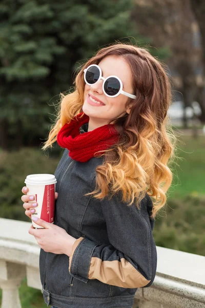 Lykkelig ung kvinde i solbriller, drikker kaffe udendørs - Stock-foto