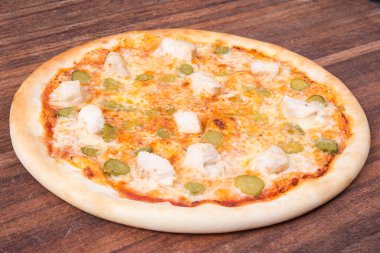 Sıcak pizza dilimi, erimiş peynirle ahşap bir masada.