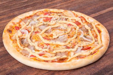 Sıcak pizza dilimi, erimiş peynirle ahşap bir masada.