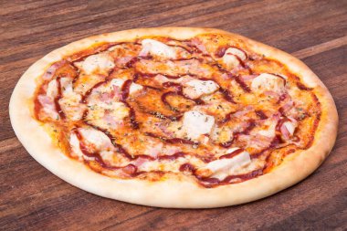 Sıcak pizza dilimi, erimiş peynirle ahşap bir masada.