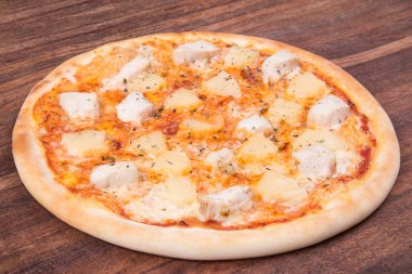 Sıcak pizza dilimi, erimiş peynirle ahşap bir masada.