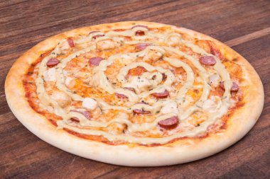 Sıcak pizza dilimi, erimiş peynirle ahşap bir masada.